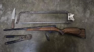 Iba por un camino rural con una escopeta, una pinza y una sierra para faena