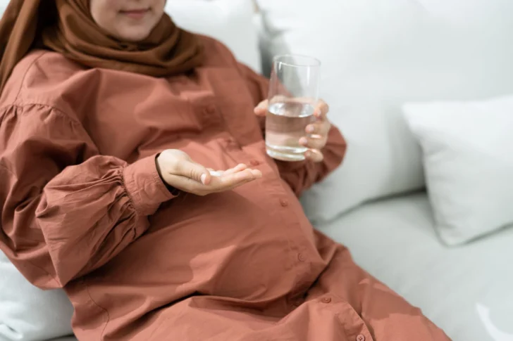 82666764_pregnant-muslim-woman-taking-folic-acid-pill-728x485